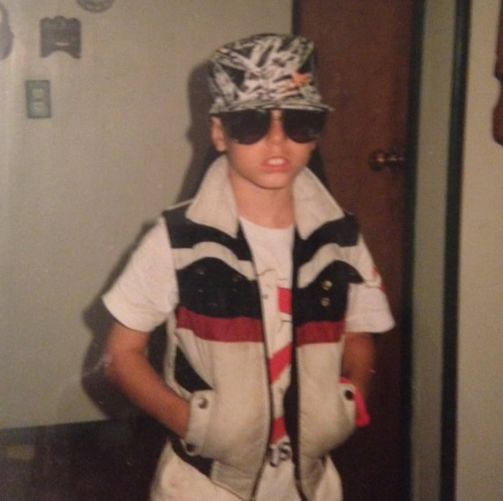 A portrait of the young artist as a cool dude. 8 year old Jon Jackson with an 80s style vest on, a ghost busters t-shirt, radical shades and a splatter painted hat. This dude is too cool for school. That being said. He loves school. 
